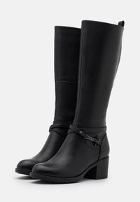 Botas de cuero negras hasta la rodilla con tacón grueso. Las características incluyen una correa decorativa con detalles en cadena y un acabado liso y pulido.