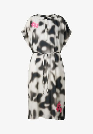 Losse korte mouw jurk met zwart-wit abstract patroon, knopen aan de voorkant, taille-ceintuur en kleine roze bloemaccenten op de borst en zoom.
