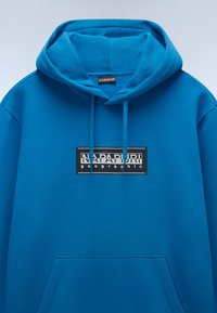 Felpa blu con cappuccio, tasca frontale e logo rettangolare nero a contrasto con la scritta "NAPAUR". Texture morbida del tessuto.