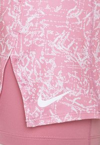Pantalones cortos deportivos rosas con un patrón abstracto blanco y el logo de Nike. Las características incluyen una abertura lateral y una cinturilla texturizada. Fabricados con tela elástica.