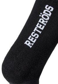 Sort sok lavet af strikket stof med hvidt vævet tekst "RESTERÖDS" på siden. Glat tekstur, midt på læggen længde, minimalistisk design.