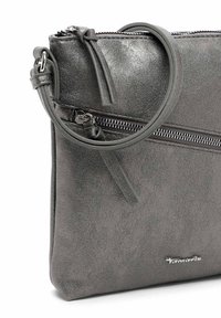 Šedá kabelka z faux kůže s texturovaným povrchem, vyznačující se zipovým uzávěrem, kruhovou rukojetí a logem na přední straně.