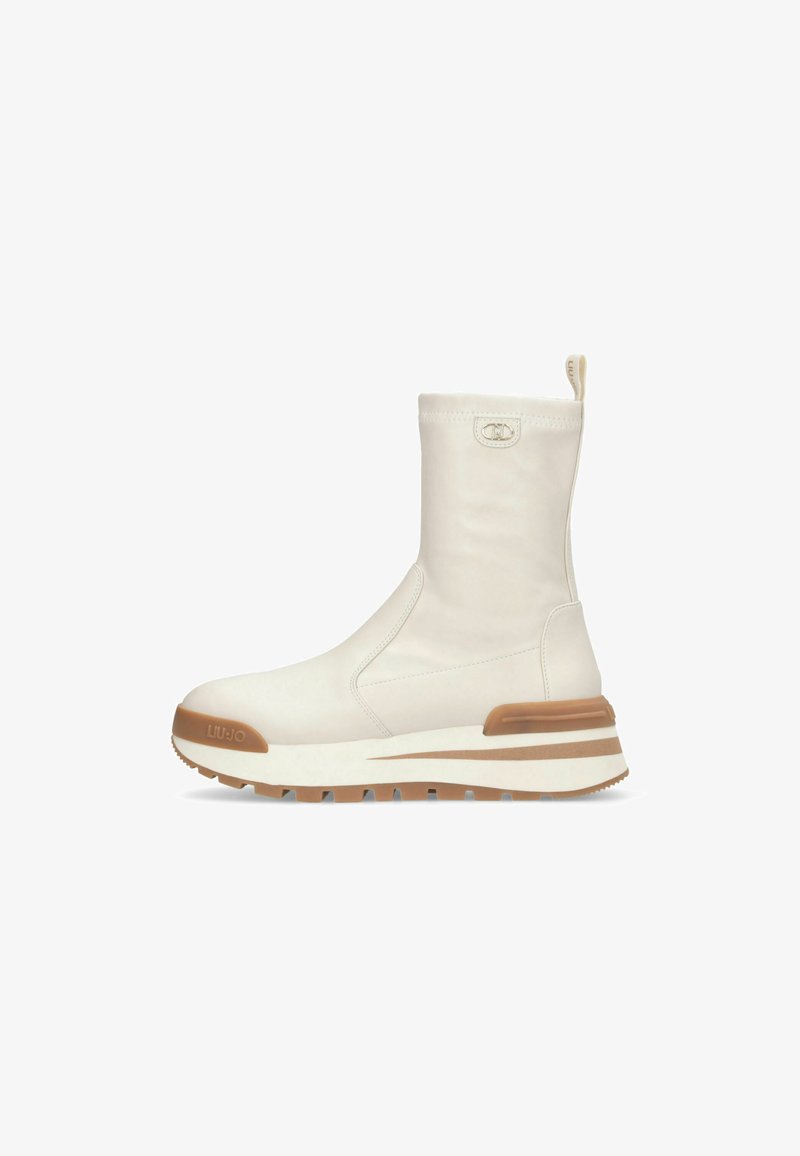 Witte enkelboots met een gladde textuur, een ronde neus en een contrasterende tan rubberen zool. Beschikt over een trekband en subtiele logo-details.