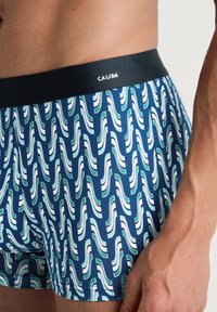 Marineblauwe herenboxershorts met een golvenpatroon in groen en wit. Zachte stof met een zwarte merkband voor comfort.