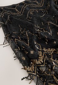 Black scarf featuring intricate geometric patterns, adorned with gold sequins and beading, finished with fringe detailing. Lightweight fabric.
