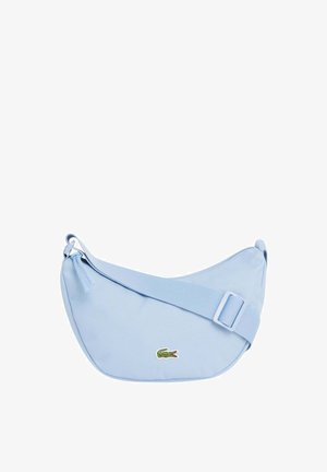 Lichtblauwe kruislingse tas in halve maanvorm met verstelbare riem en klein groen krokodillenlogo aan de voorkant.