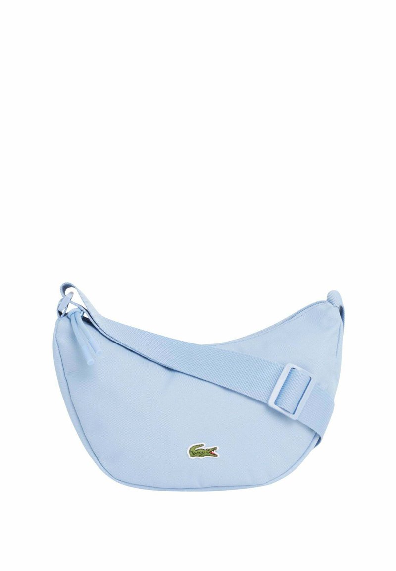 Sac bandoulière bleu clair en forme de croissant avec une sangle réglable et un petit logo crocodile vert sur le devant.