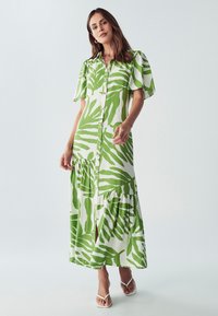 Maxi šaty z bílé látky s potiskem zelených listů, krátké nafouknuté rukávy, knoflíky vpředu a sukně s vrstveným designem.