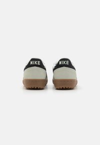 Nike sneakers with a black and gray suede upper, white accents, and a gum outsole. The heel features 'NIKE' in white lettering.