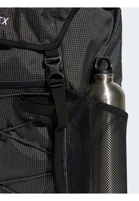 Black backpack featuring a grid pattern, adjustable straps, and a side mesh pocket holding a stainless steel water bottle.