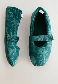 Teal samta Mary Jane čības ar ziedu damaskas rakstu un auduma siksnu, skatītas no augšas un sāna uz gaiša fona.