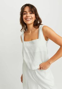 Lys grøn linned tanktop med firkantet udskæring og brede stropper, parret med matchende løstsiddende bukser. Har et enkelt, struktureret design.