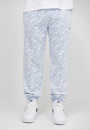 Light blue joggers with a repeating white logo pattern, featuring ribbed cuffs and a relaxed fit. Paired with white sneakers.