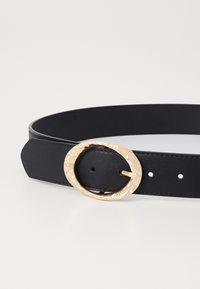 Curea din piele neagră cu o bandă lată, având o cataramă circulară aurie, ciocănită, și găuri uniform amplasate pentru ajustare.