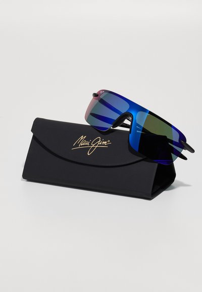 Lunettes de soleil avec une grande monture bleue et des verres dégradés rose à vert, reposant sur un étui noir arrondi avec un logo doré.