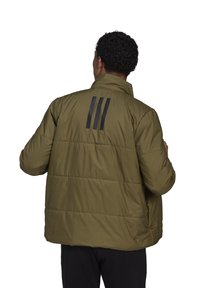Giacca imbottita verde oliva con colletto alto, caratterizzata da strisce nere sul retro, tasche con zip e una texture liscia.