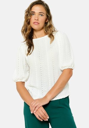 White short-sleeve blouse with a textured, knitted pattern and small eyelet details, featuring a round neckline and relaxed fit.