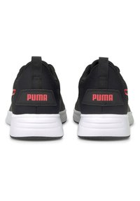 Zapatillas deportivas negras con parte superior de tela texturizada, suelas blancas y llamativo logo rojo de "PUMA" en el talón. Incluye una pestaña para facilitar el calzado.