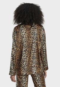 Pj-set i leopardmönster med lättviktig tyg, oversize passform, långa ärmar och kontrasterande sidostripes på byxorna.