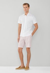 Biela krátka rukávová košeľa na gombíky, ružové šortky s jemnými pruhmi a hnedé espadrilky na pásky. Jednoduchý, neformálny letný outfit.