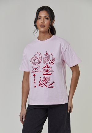 Lichtroze katoenen T-shirt met gedurfde rode opdrukken van harten, taart, een carrousel, een envelop en een engel met pijl en boog.