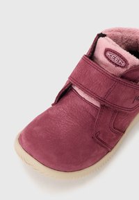 Bordowe skórzane buty z miękkim różowym wykończeniem, z rzepem i teksturowaną powierzchnią. Okrągły czubek i elastyczna beżowa podeszwa.