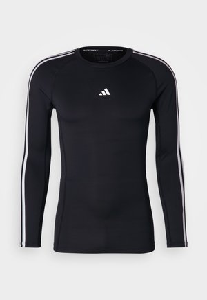 Black long-sleeve athletic shirt with a fitted design. Features a white Adidas logo on the chest and white stripes along the shoulders.