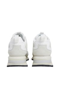 Scarpe sportive bianche con una parte superiore in suede e mesh, dotate di una linguetta, colletto imbottito e una striscia di accento grigia sulla suola intermedia.