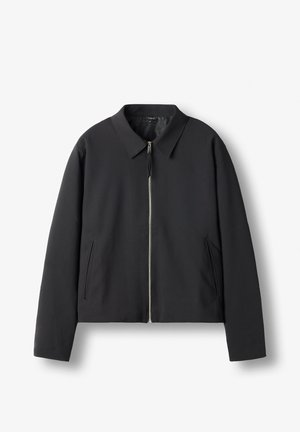 Schwarze Zip-Jacke mit Kragen und zwei vertikalen Seitentaschen, flach auf weißem Hintergrund dargestellt.