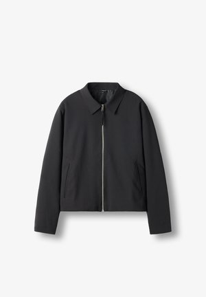 Schwarze Zip-Jacke mit Kragen und zwei vertikalen Seitentaschen, flach auf weißem Hintergrund dargestellt.