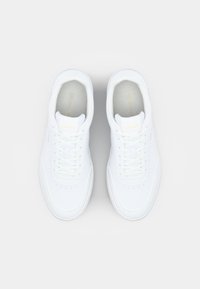 Valkeat tennarit, joissa on sileä, nahkamainen pinta. Ne ovat pyöreäkärkiset, edestä nauhoitettavat ja niissä on hienovarainen kultainen logo kielen kohdalla.