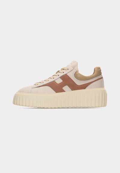 Baskets compensées beige et marron avec semelle épaisse côtelée, fermeture à lacets et accents en daim sur fond neutre.