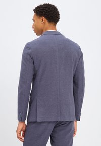 Heren op maat gemaakte blazer in gestructureerde donkerblauwe stof; heeft een enkele split, notch-kleppen en accenten van vier knopen op de manchetten.