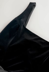 Czarna aksamitna sukienka z eleganckim, jedno-ramiennym fasonem, o gładkiej fakturze i lekko drapowanym kroju.