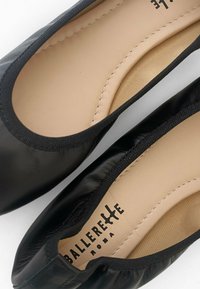 Ballerine in pelle nera con punta arrotondata, bordo elasticizzato e rivestimento interno liscia. Marchio visibile all'interno della scarpa.