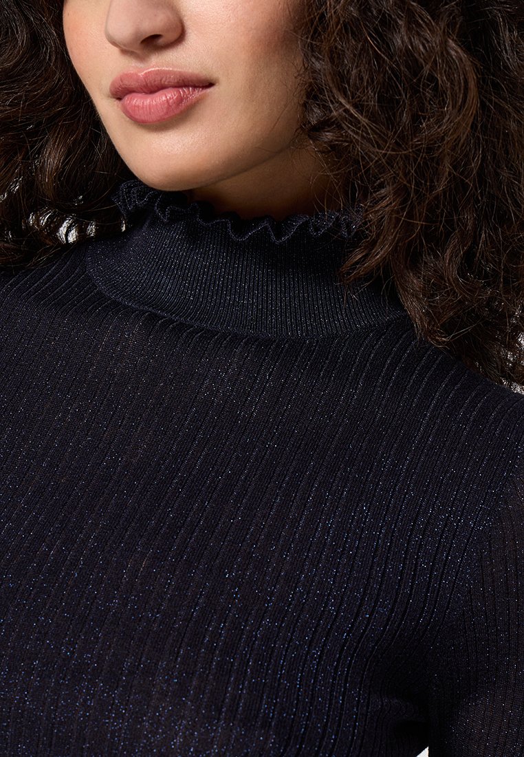 Top en maille côtelée noir avec un col haut à volants. Le tissu a un léger éclat, créé par de fins fils métalliques intégrés.