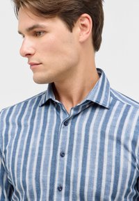 Camicia a righe verticali blu e bianche realizzata in un materiale morbido, con colletto all'inglese e bottoni blu scuro.