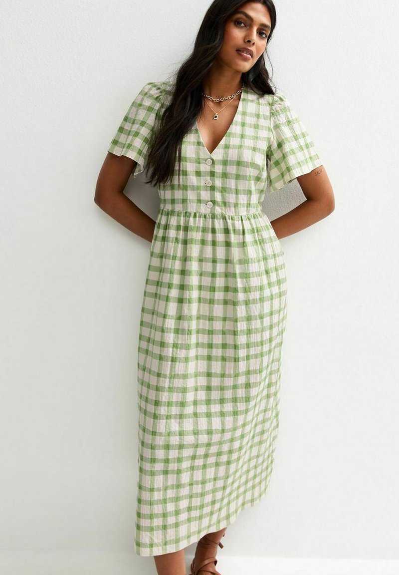 Grün-weiß kariertes Midi-Kleid mit kurzen Ärmeln, V-Ausschnitt, Knopfleiste und einem elastischen Taillenbund. Gleiche, leichte Stoffqualität.