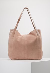 Grand sac fourre-tout en daim rose avec deux anses en cuir et coutures apparentes. Texture douce et design spacieux adapté à un usage quotidien.