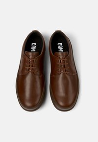 Brown leather shoes with a smooth finish, rounded toe, five eyelet lace-up design, and a black cushioned insole featuring "CAMPER" branding.