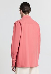 Langärmliges Hemd aus weichem Korallstoff, mit Kentkragen, vollem Rücken und seitlichen Schlitzen für Bewegungsfreiheit, ausgestattet mit knöpfbaren Manschetten.