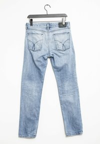 Ljusblå denim skinny jeans med medelhög midja, bakfickor och urtvättningar på benen. Hänger från en svart plastgalge.