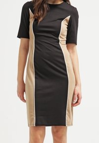 Black and tan color-blocked dress with short sleeves, featuring white contrast piping along the seams and a fitted silhouette.