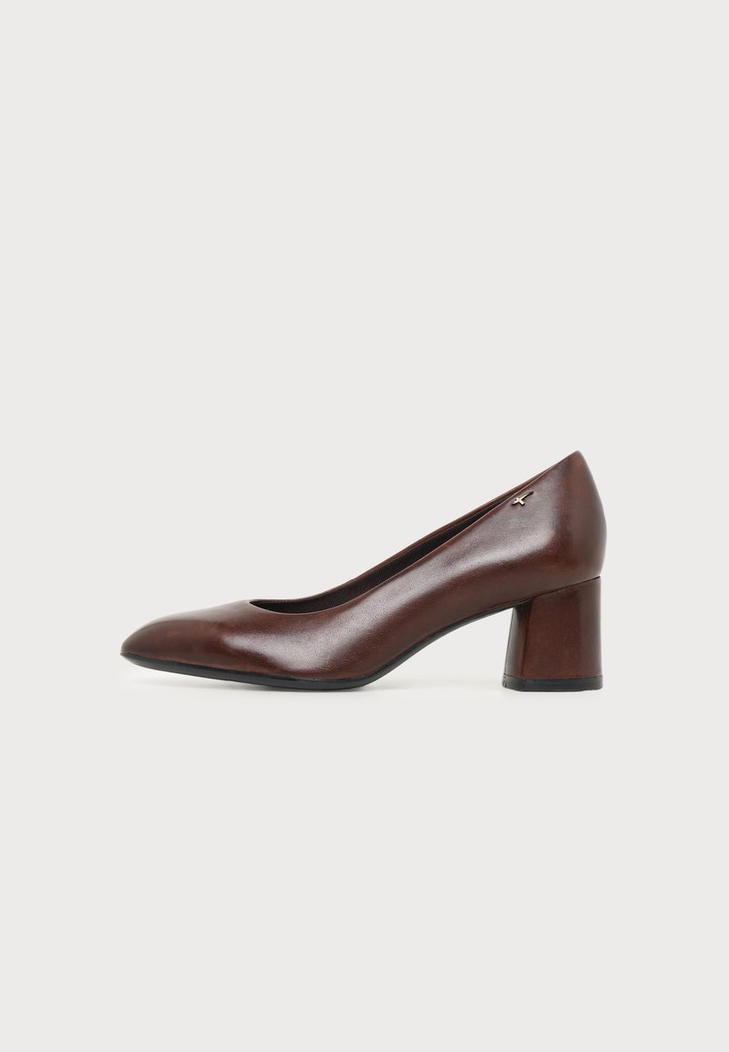 Escarpin en cuir marron à petit talon bloc, bout arrondi et petit logo métallique près du talon, présenté de profil sur fond blanc.
