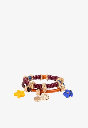 Dwie nałożone na siebie bransoletki z bordową spiralką, pomarańczową nicią, koralikami w kolorze złota oraz zawieszkami, w tym żółtą gwiazdą, niebieskim kwiatem i teksturowanymi złotymi monetami.
