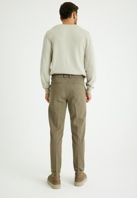 Hellgrau sweatshirt, braune strukturierte Hose und beigefarbene Sneakers. Lässige Passform, schlichtes Design mit geradem Schnitt. Keine sichtbaren Muster oder Logos.