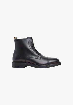 Bottines en cuir noir avec un bout arrondi, un laçage sur le devant et un petit talon. Elles disposent d'une languette à l'arrière et de détails de couture subtils.