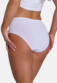 Witte katoenen slips met kanten accenten aan de zijkanten, hooggekapselde design, zachte textuur en golvende rand langs de tailleband.