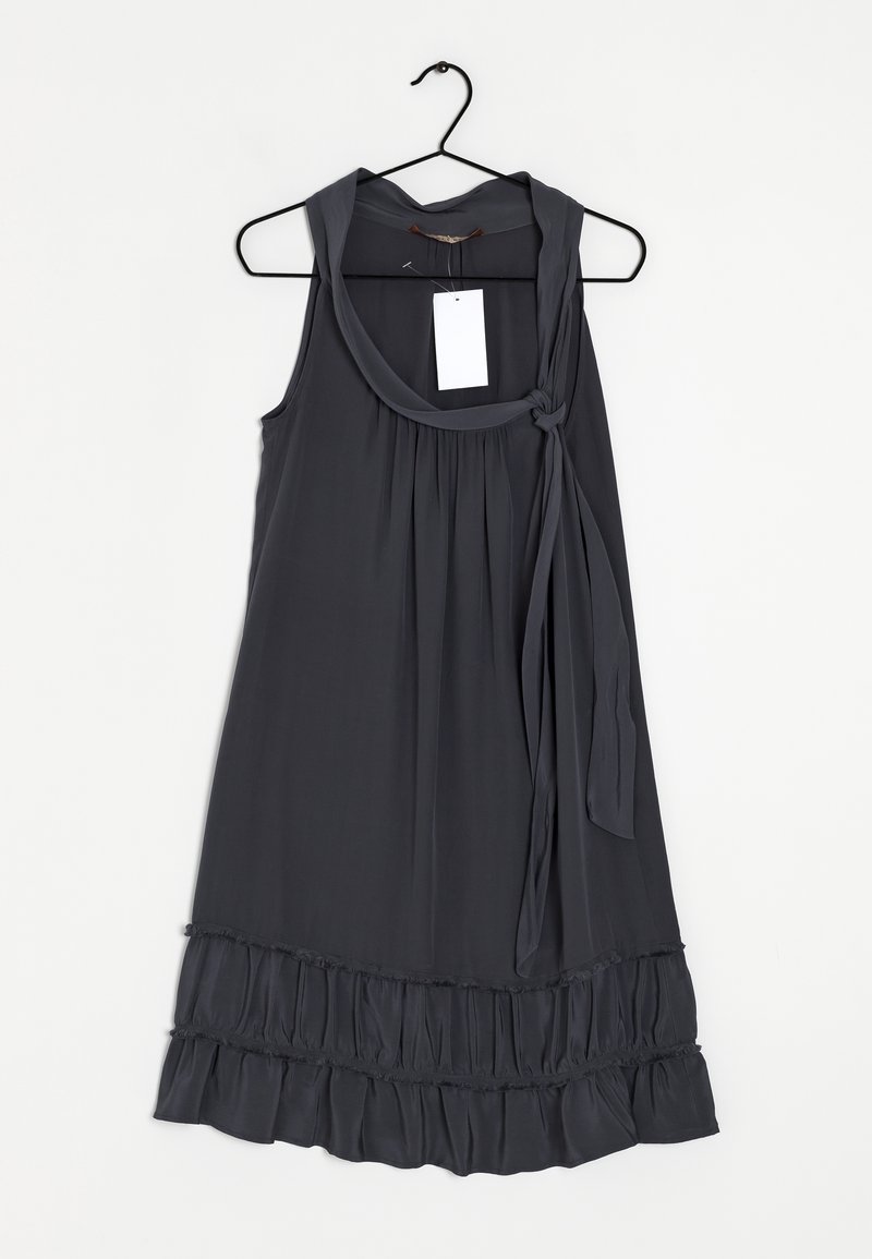 Robe sans manches gris foncé avec ourlet à volants et foulard noué autour du cou, suspendue sur un cintre noir avec une étiquette blanche sur fond blanc.