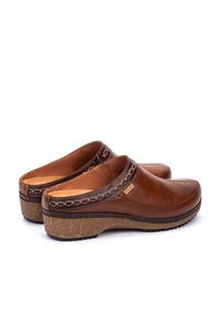 Sabots en cuir marron avec un bout arrondi, des coutures décoratives et une semelle en liège contrastante. Ils possèdent un petit talon et un design sans lacets.